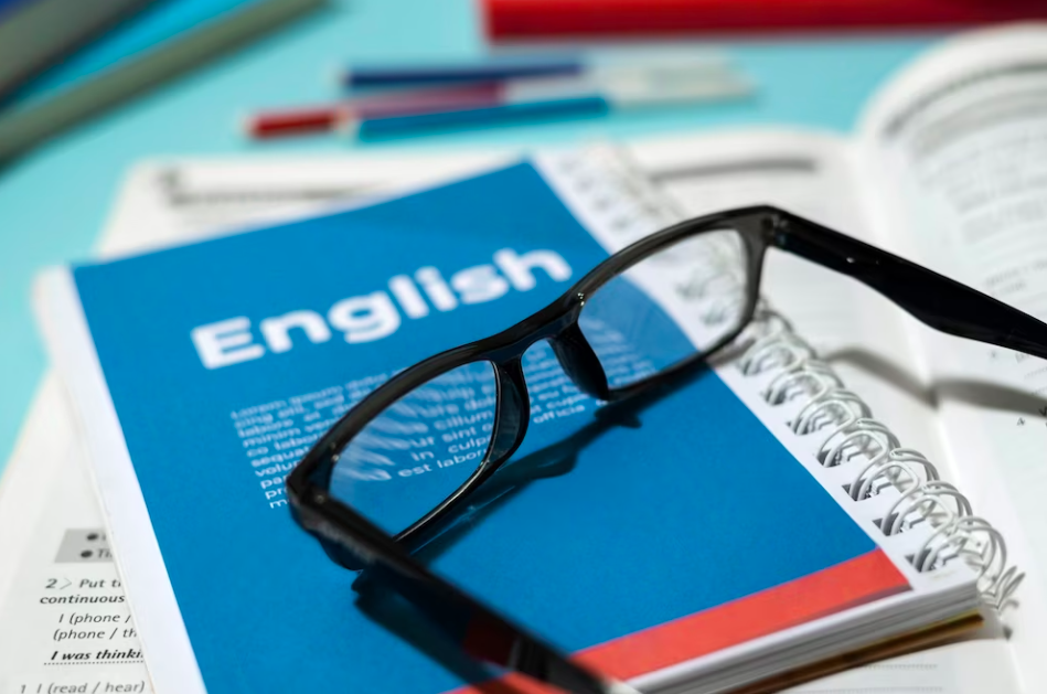 English book with glasses on table, symbolising study materials for IELTS test preparation.