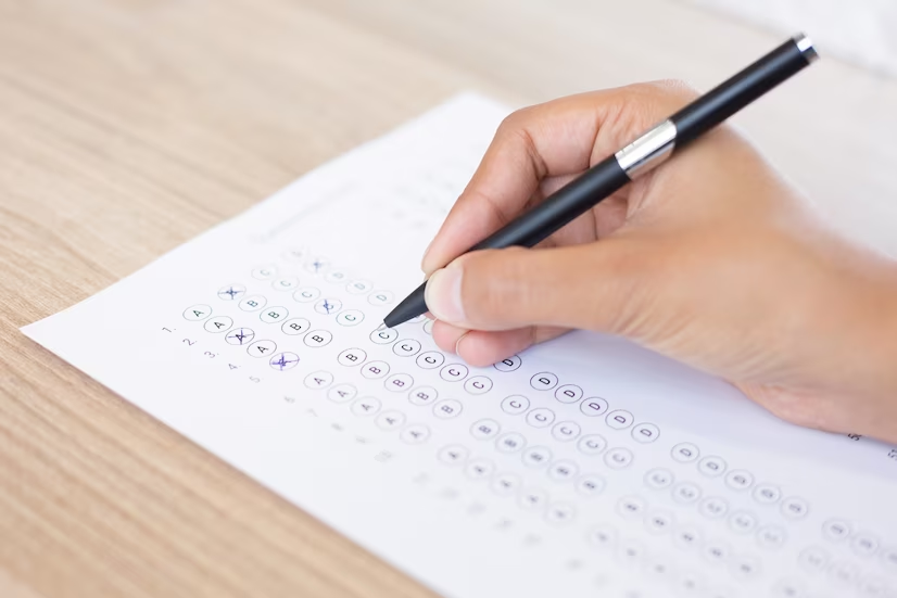 Close-up of a person filling out an exam questionnaire for IELTS test preparation.