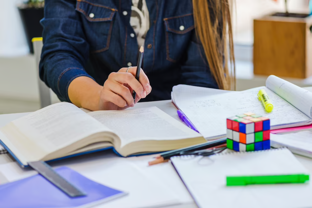 Woman studying for TOEFL exam with books and notes, at table.